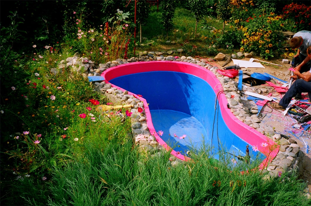 Пластиковый бассейн для дачи не традиционной формы, с большим количеством закруглений. Были использованы пластиковые материалы красного и синих цветов. Использование природного камня для обкладки бассейна превосходно украшает дачный ландшафт.